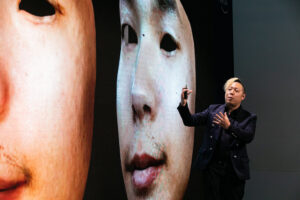 Man presenting screen with distorted faces on them