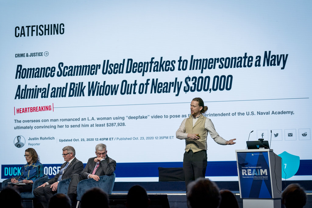 Person giving a presentation with a headline about deepfakes on the screen behind them